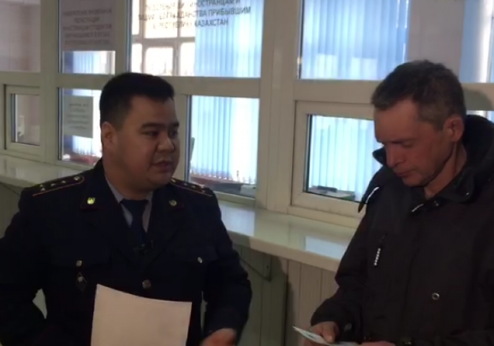 Сотрудник миграционной полиции вручает Юрию Образцову документ о временной регистрации.