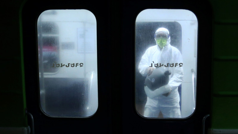 Мужчина в защитном костюме распыляет дезинфицирующее средство в метро Еревана. © Reuters