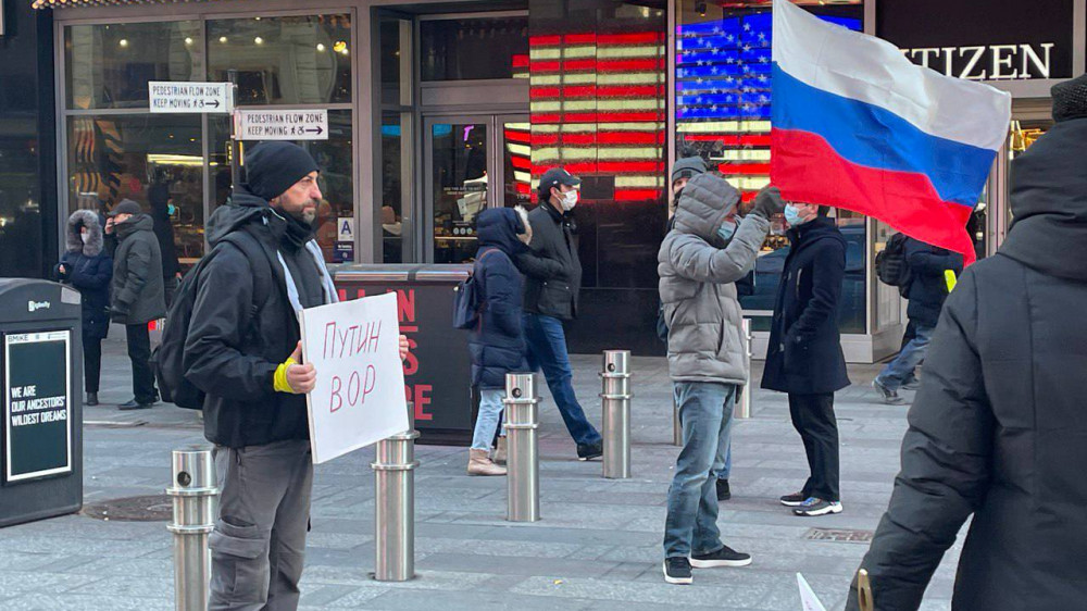 Протестующий держит плакат на Таймс-сквер в Нью-Йорке. Фото Александра Назарова