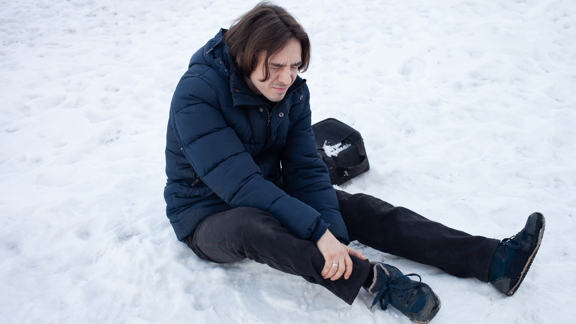 Гололед падает. Поскользнулся зимой. Мужчина поскользнулся на льду. Мужчина падает на скользком снегу.